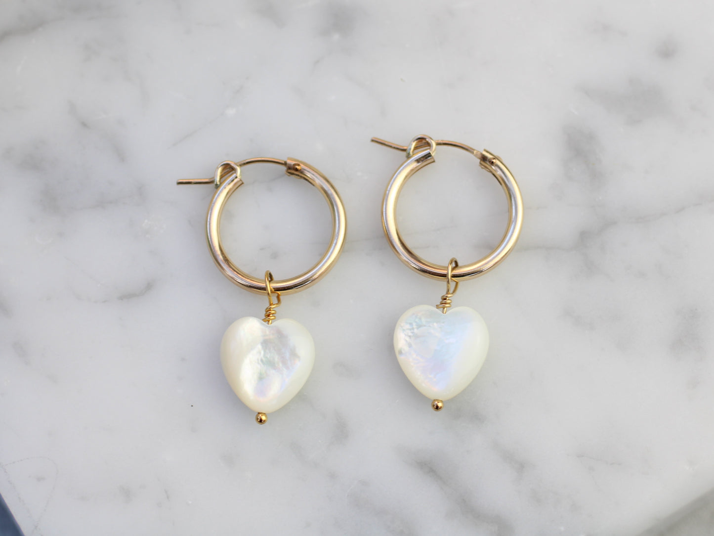 Gold hoop earrings with mother of pearl heart charm.