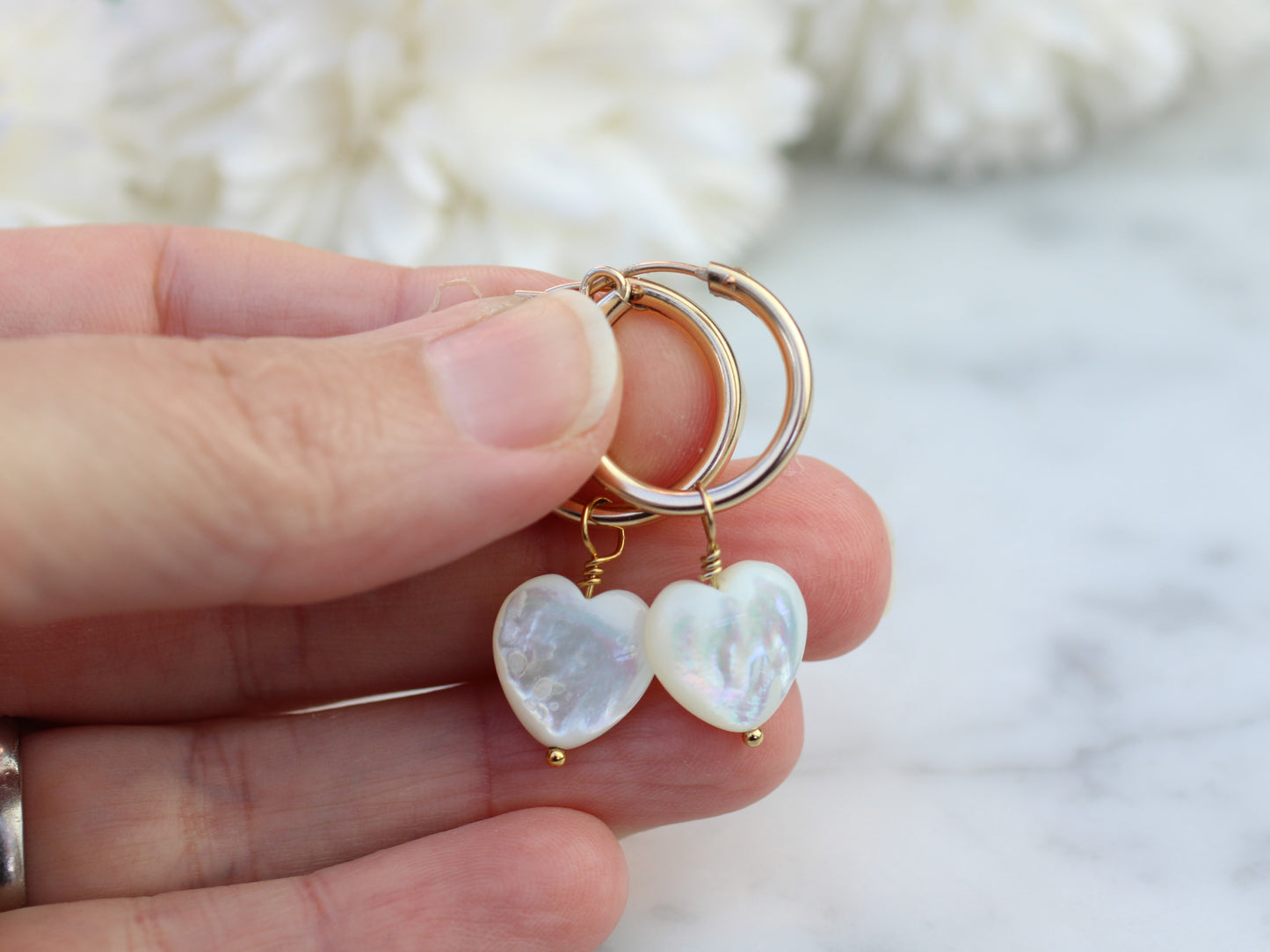 Gold hoop earrings with mother of pearl heart charm.