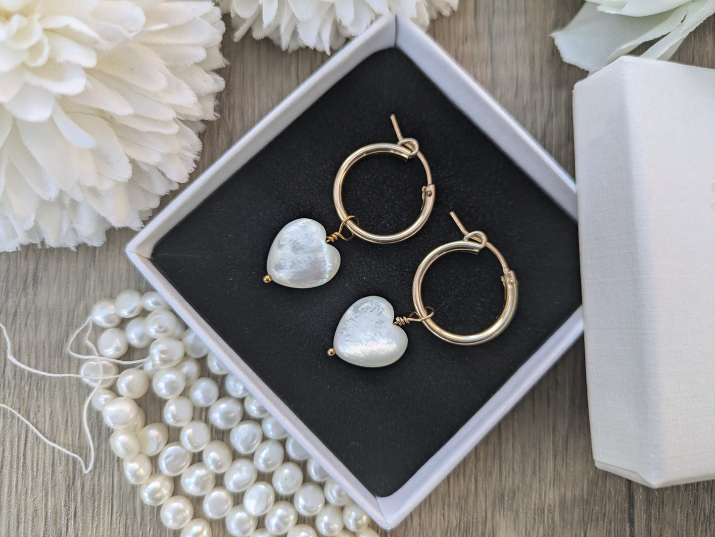 Gold hoop earrings with mother of pearl heart charm.